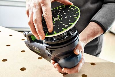 Een vakman monteert de steunschijf op een Festool-schuurmachine