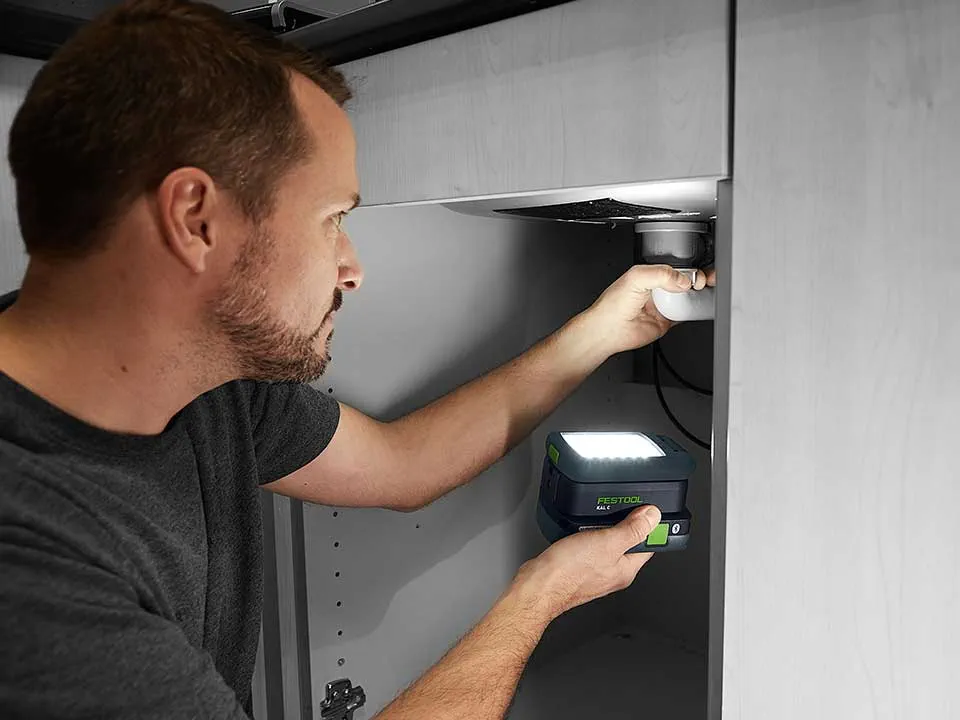 Un homme éclaire le raccord d'un lavabo avec la SYSLITE KAL 2