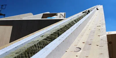 De wanden van een massief houten huis van vurenhout en verschillende isolatiematerialen.