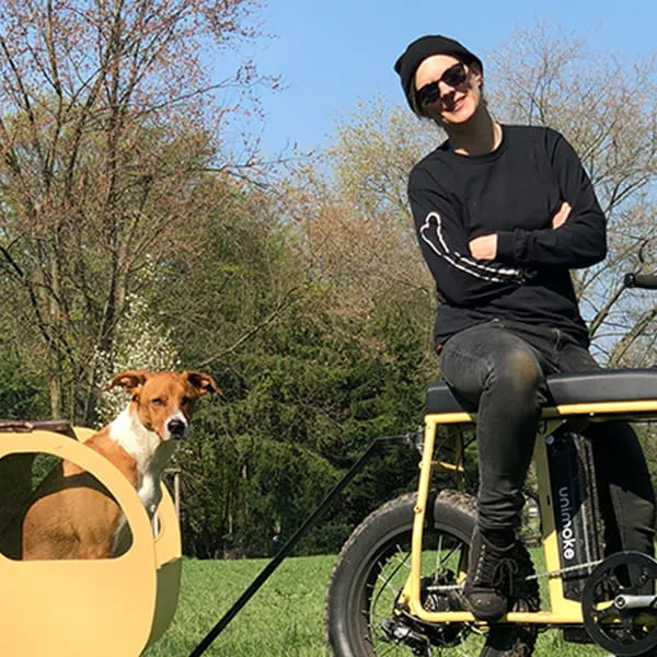 Maker Laura Kampf op een zelfgebouwde fiets met haar hond Smudo in een Tiny Trailer.