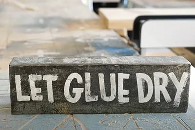 Een bord met de inscriptie Let Glue Dry.