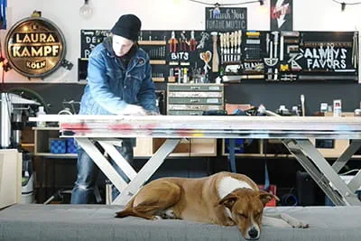 Maker Laura Kampf aan het werk in haar werkplaats met haar hond Smudo.