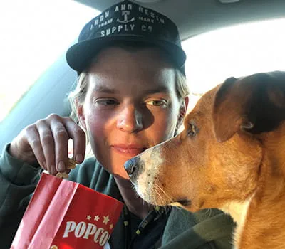 Laura Kampf eet een pak popcorn met haar hond Smudo.