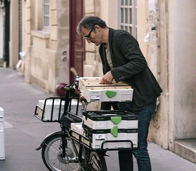 Une fois le travail terminé, cet ébéniste pas comme les autres range son atelier et enfourche son vélo pour se faufiler à nouveau dans les rues de Paris.